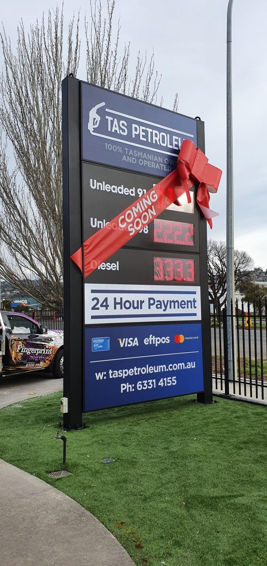 A gas station sign with a red bow on it.