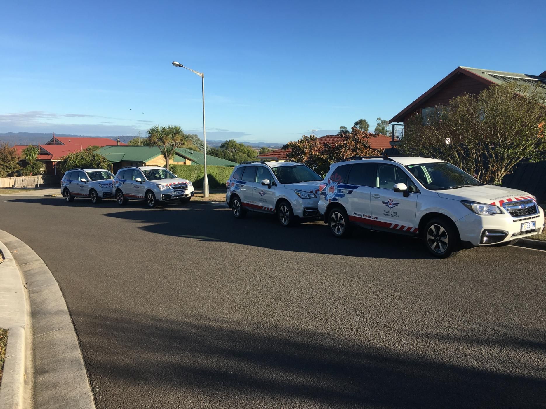 A row of cars are parked on the side of a road.