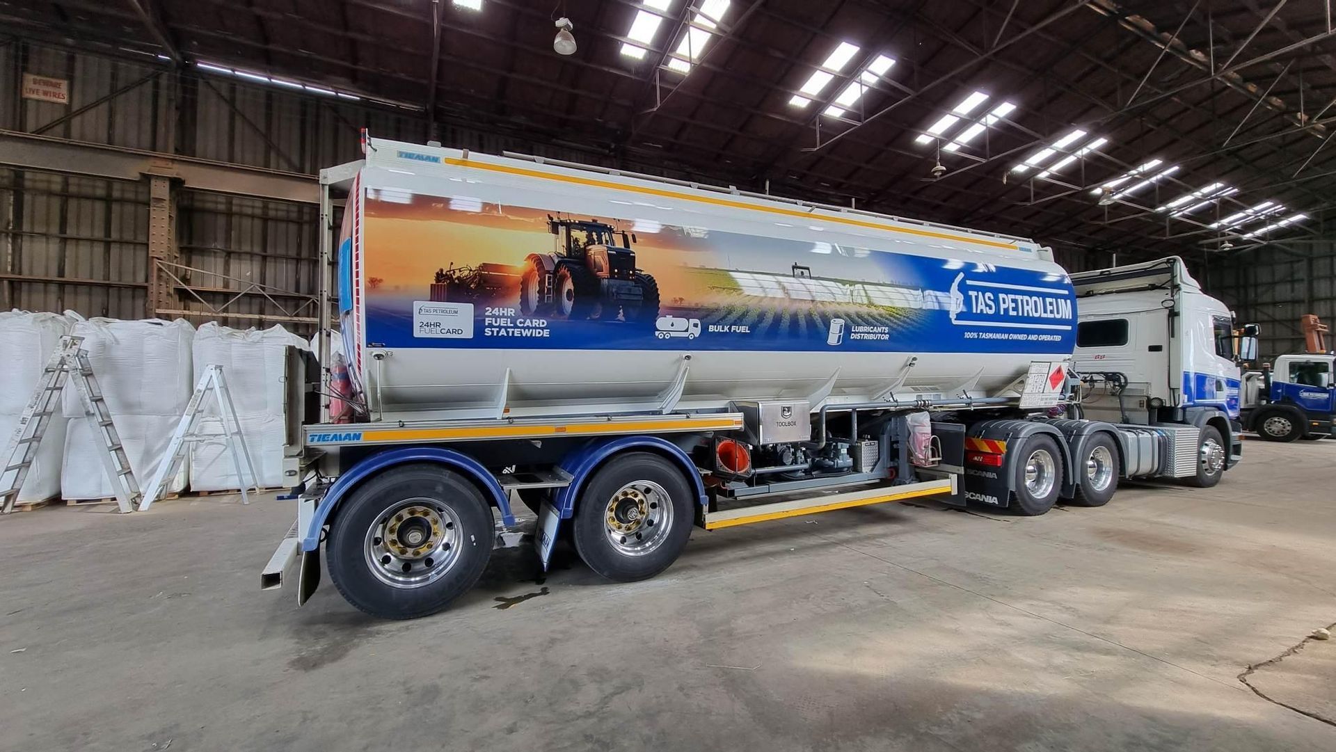 A large tanker truck is parked in a warehouse.