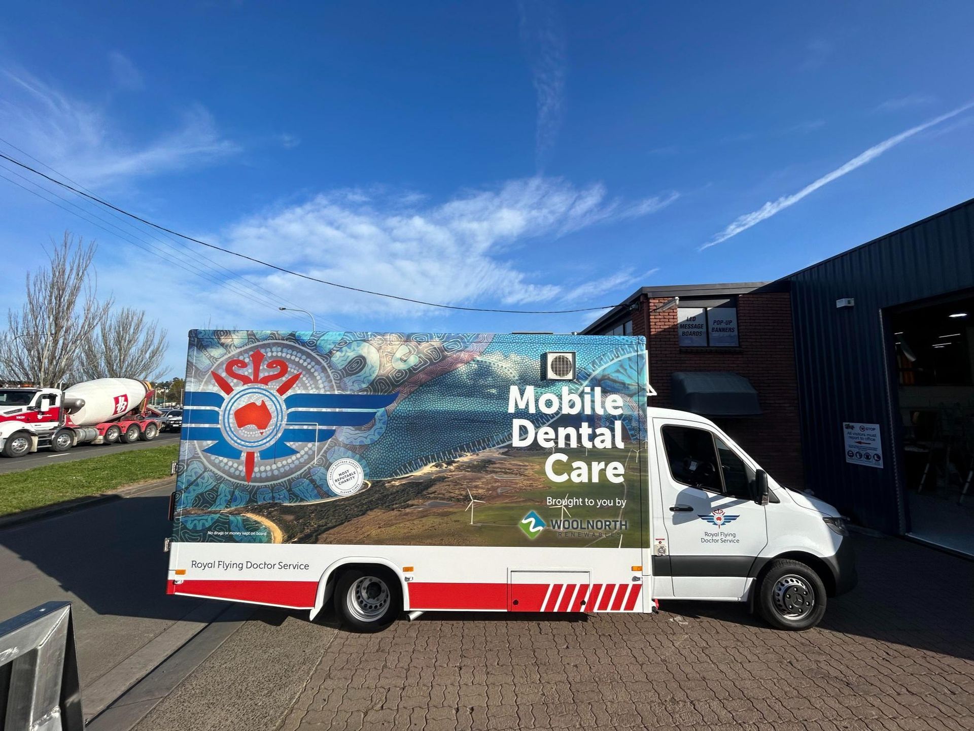 A mobile dental care van is parked in front of a building.