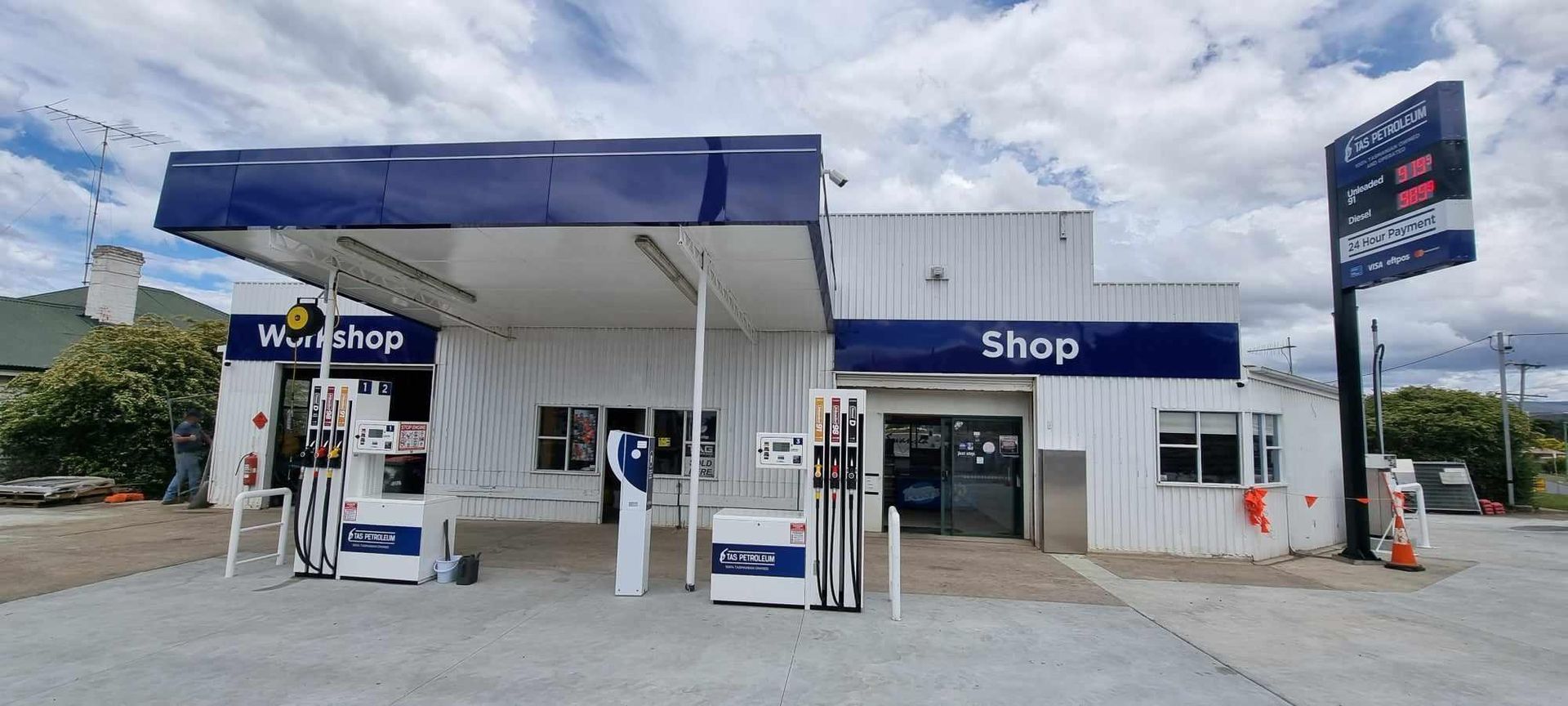 A gas station with a blue roof and a sign that says shop.