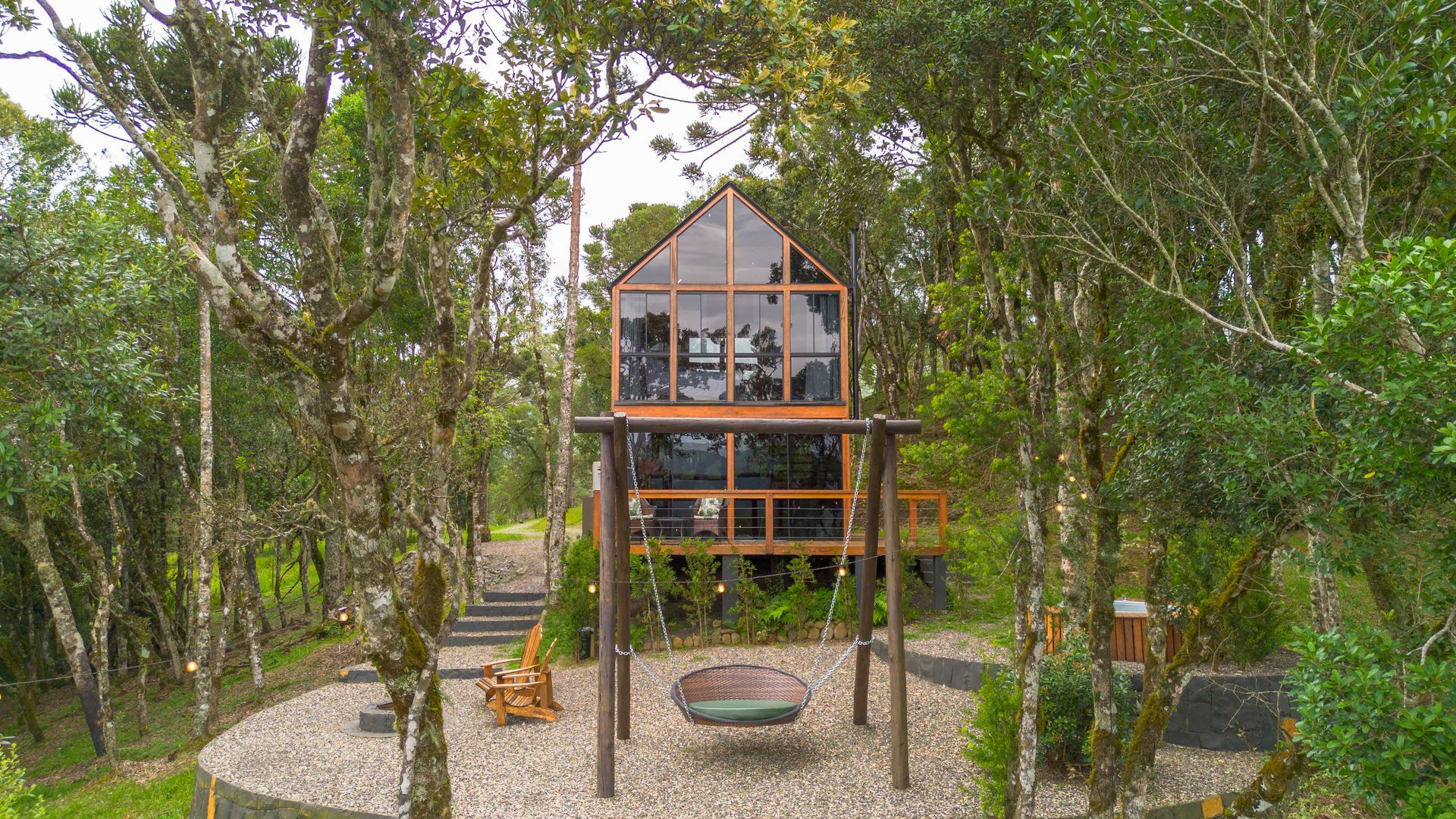 Cabana estilo casa na árvore, aninhada entre as árvores, com balanço e pátio.