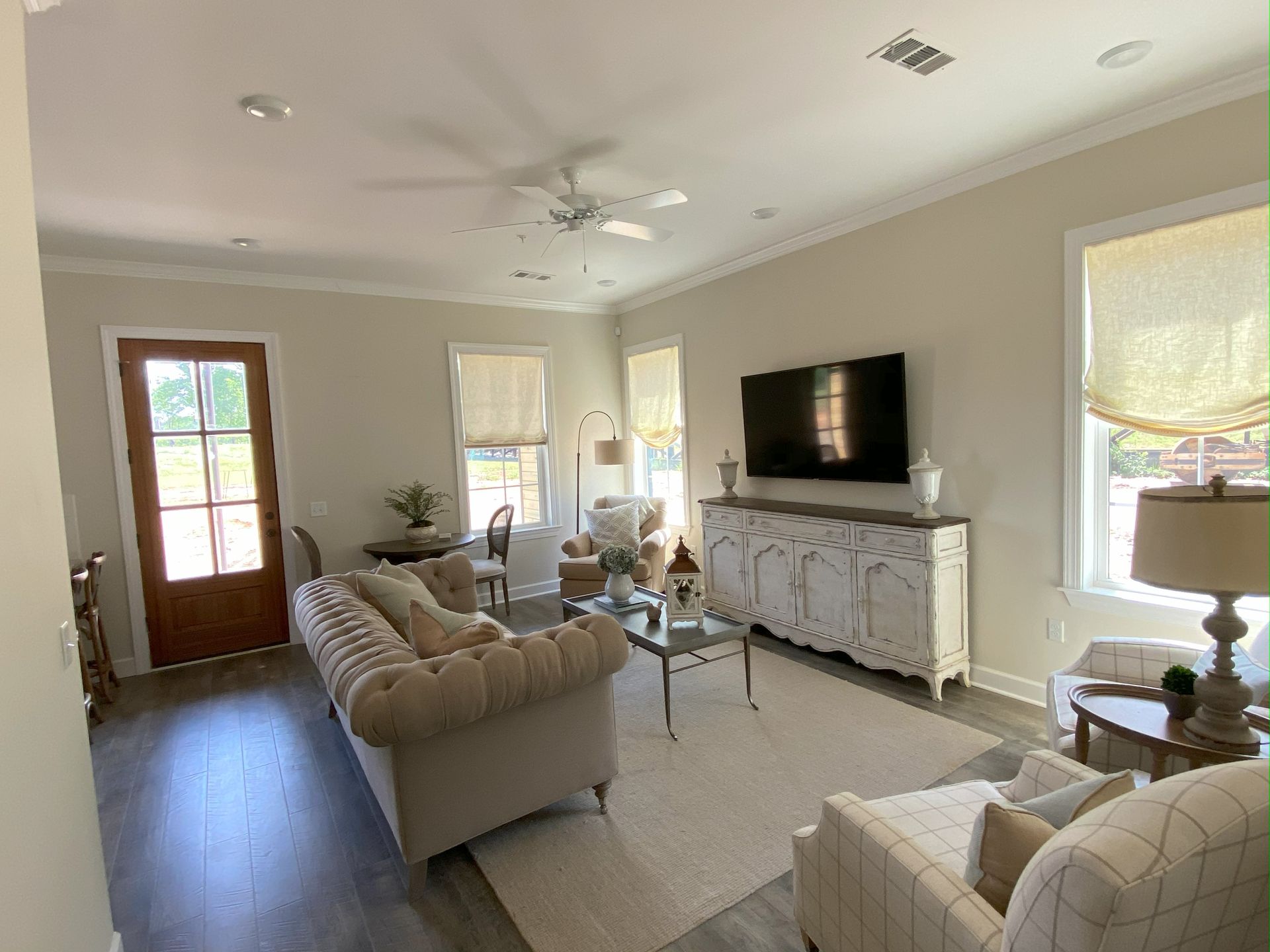 Living room with a sofa, TV, windows, and light-colored walls.