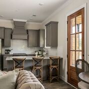 Kitchen with gray cabinets, wooden bar stools, and a brown door.