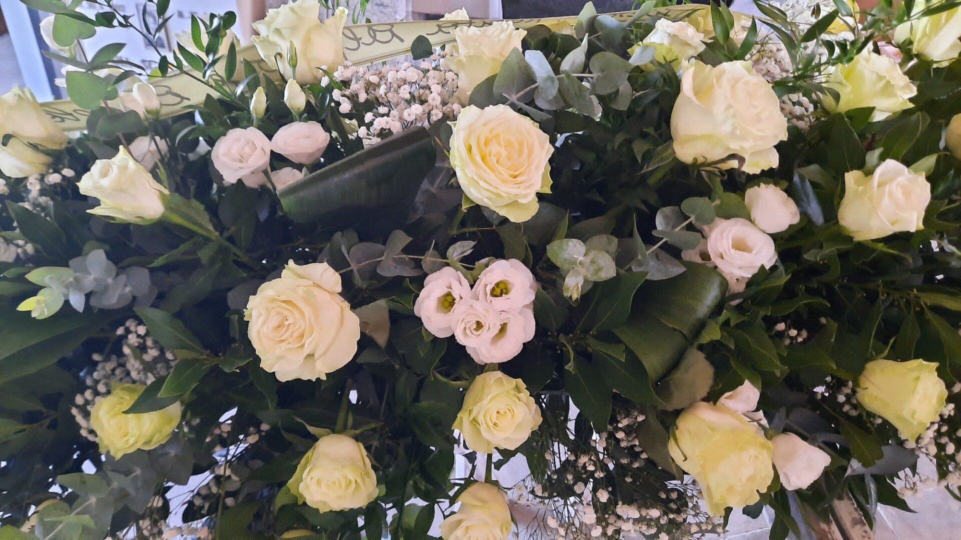 Bouquet di rose rosa pallido e color crema con verde, disposto in una composizione floreale.