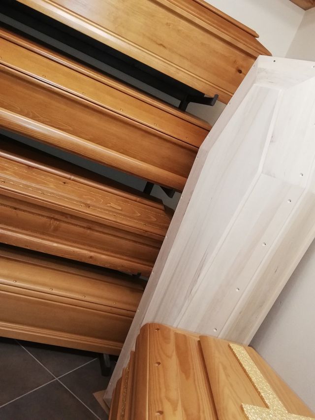 Vista angolata di una scala in legno accanto a una parete bianca e un pavimento in piastrelle scure all'interno.
