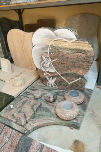 Cartello decorativo a forma di cuore con fiori bianchi su un tavolo accanto a elementi decorativi coordinati effetto pietra.