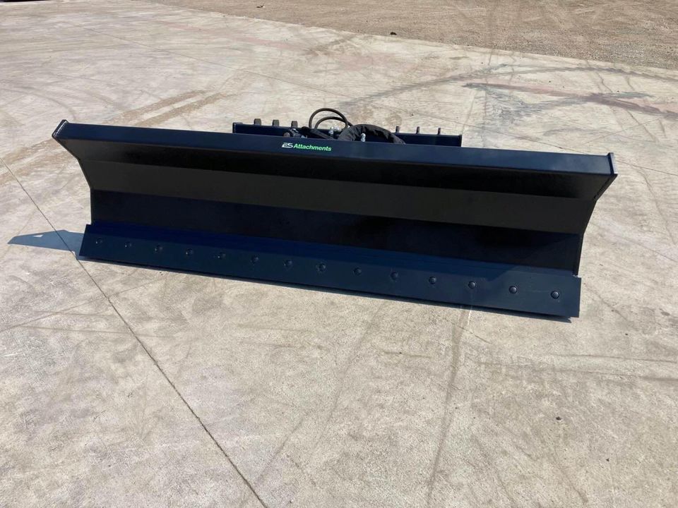 A snow plow is sitting on a concrete surface