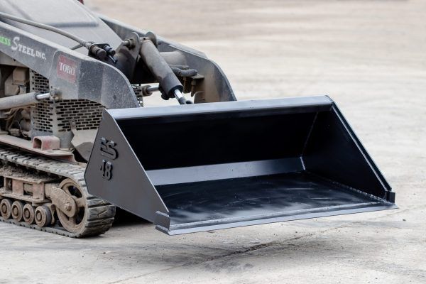 A black bucket is sitting on a concrete surface.