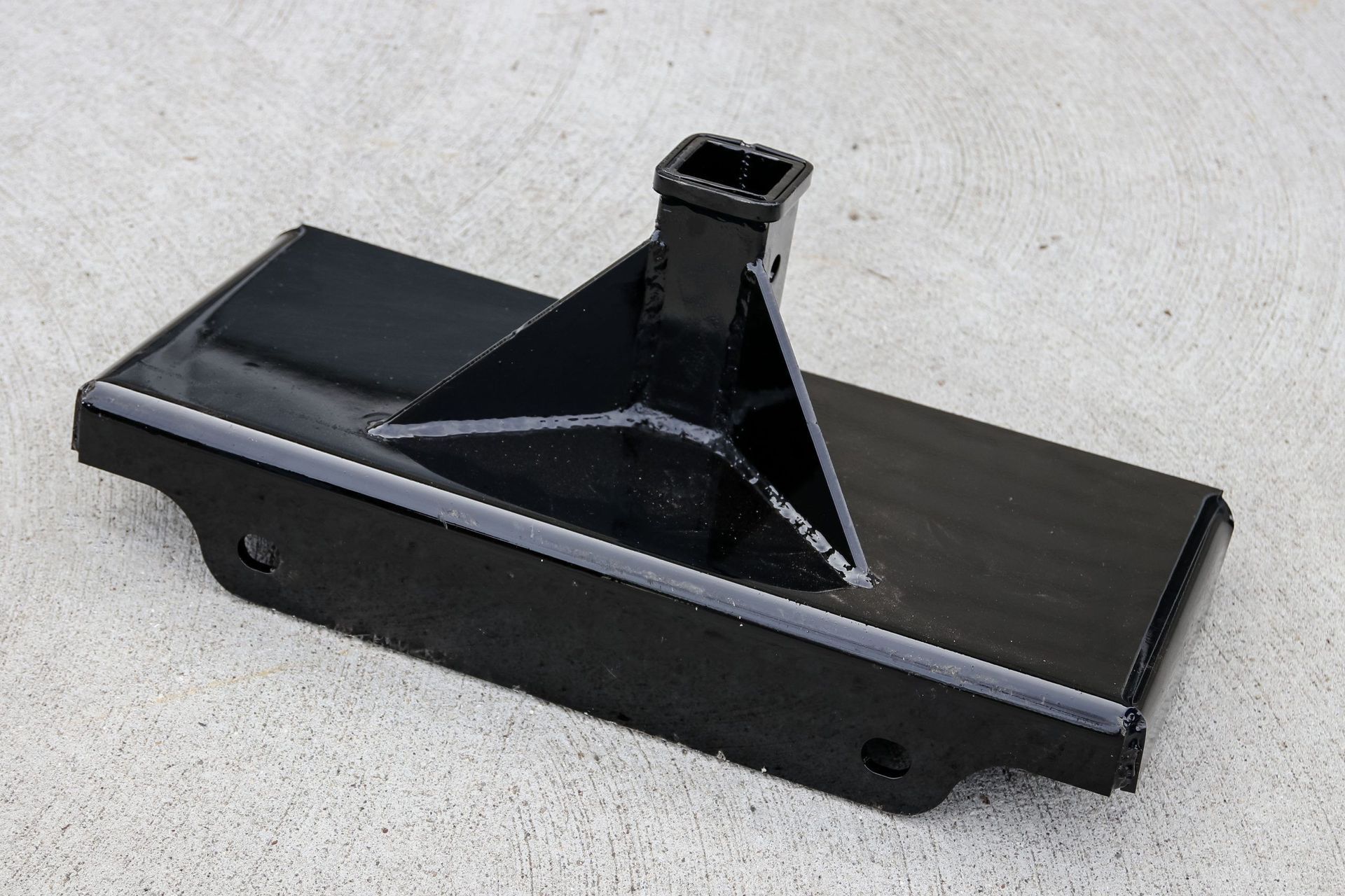 A black metal object is sitting on a concrete surface.