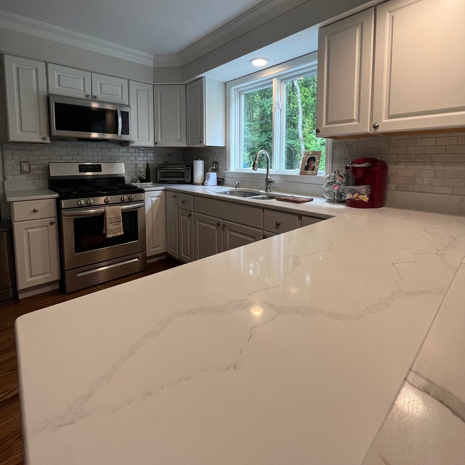 Bright modern kitchen with white cabinets, stainless appliances, and a marble island countertop