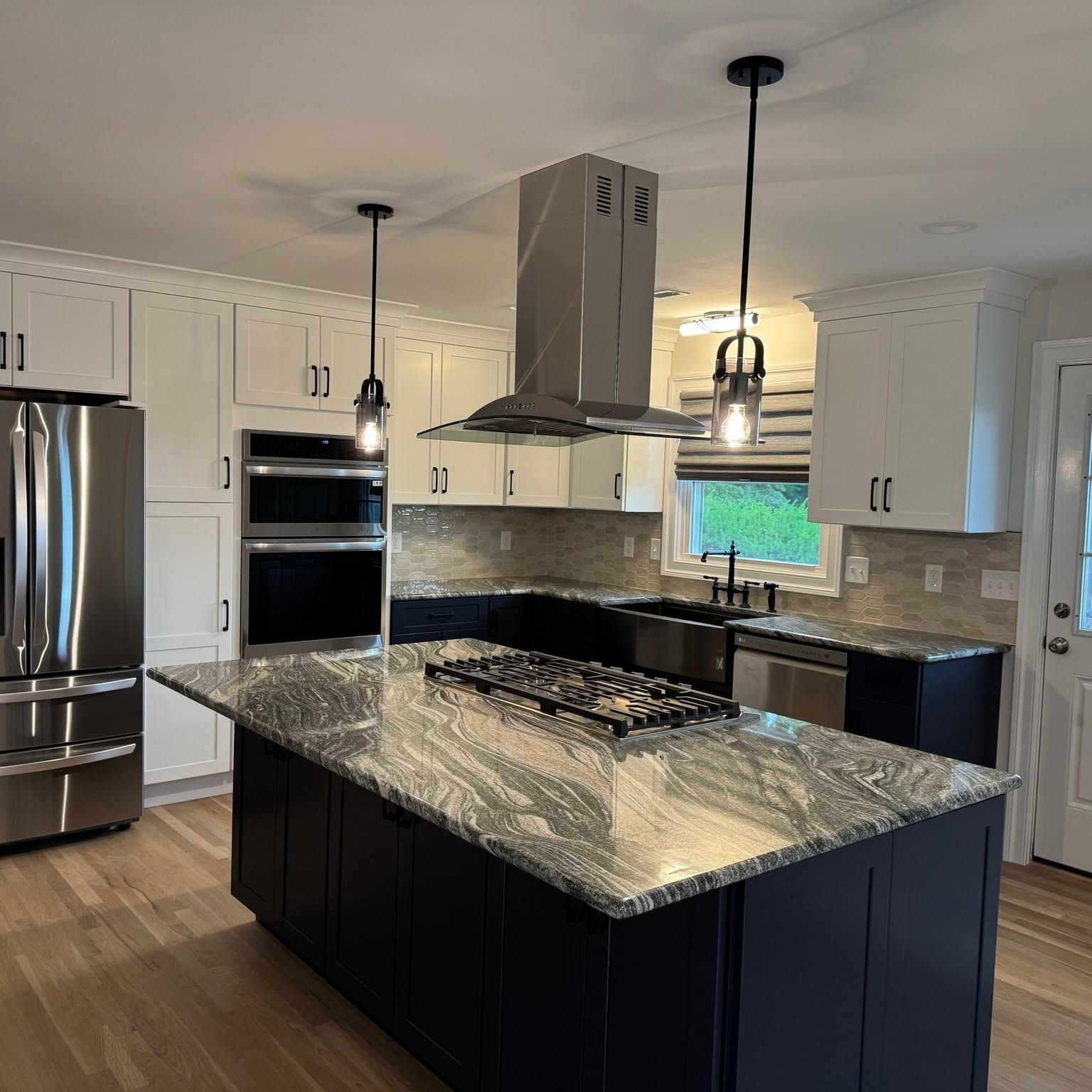 Modern kitchen with black granite island, white cabinets, stainless appliances, and pendant lights