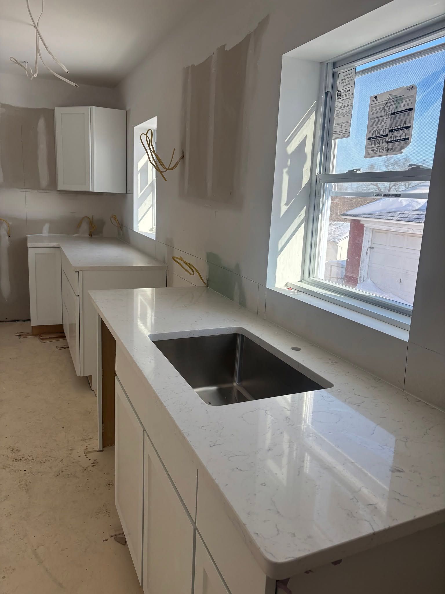 Modern kitchen with white cabinets, marble countertop, and a sink beside a bright window