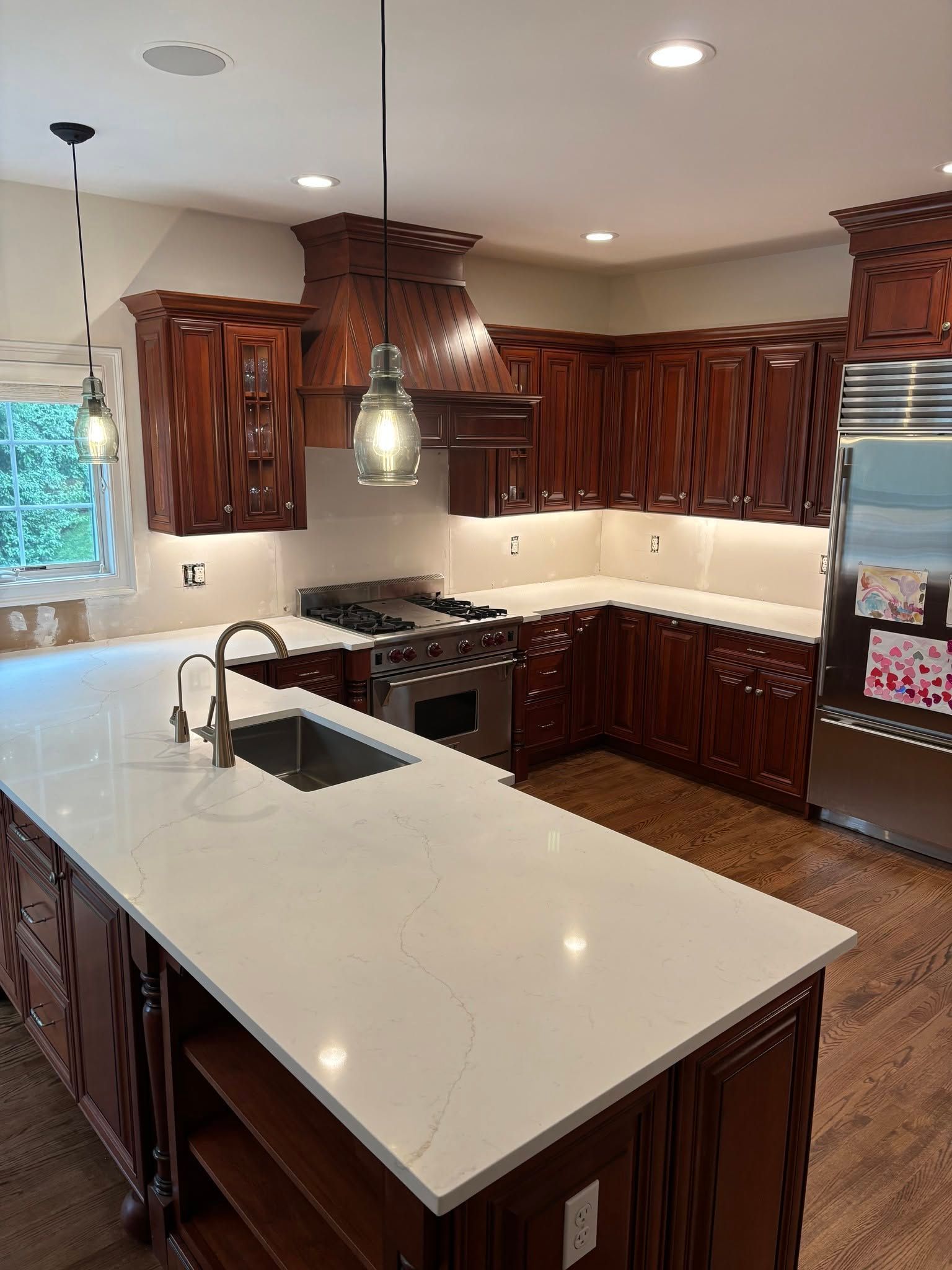 Modern kitchen with white island, dark wood cabinets, stainless appliances, and pendant lighting
