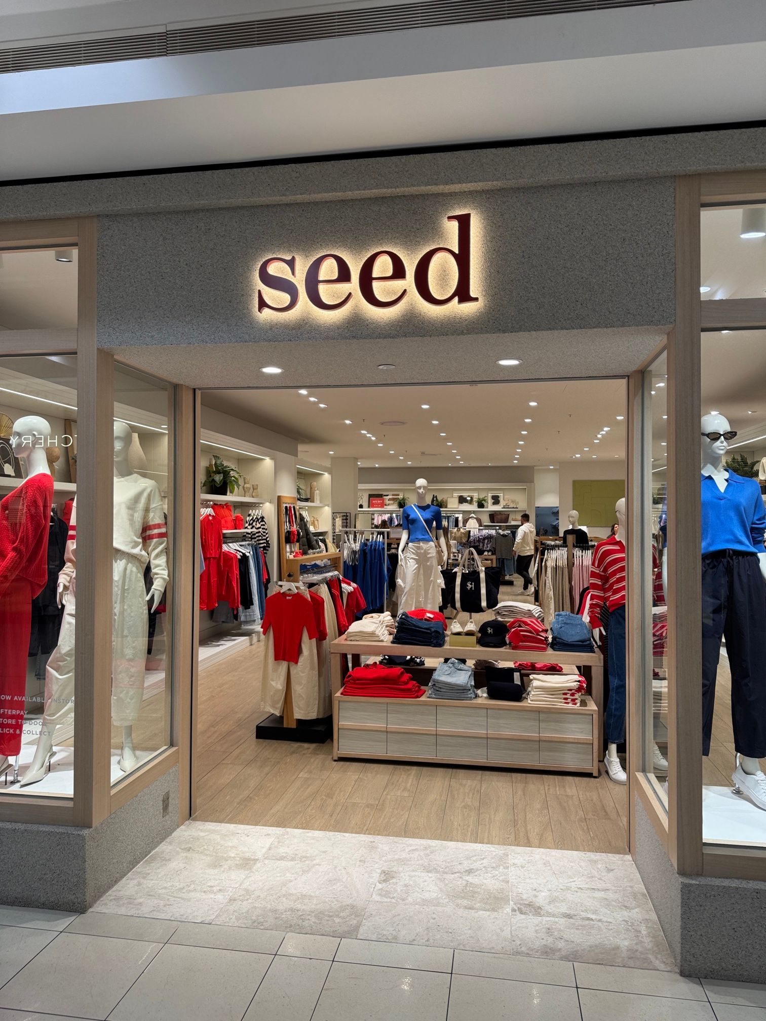 Storefront of the “seed” clothing shop with red and blue clothes on display inside.