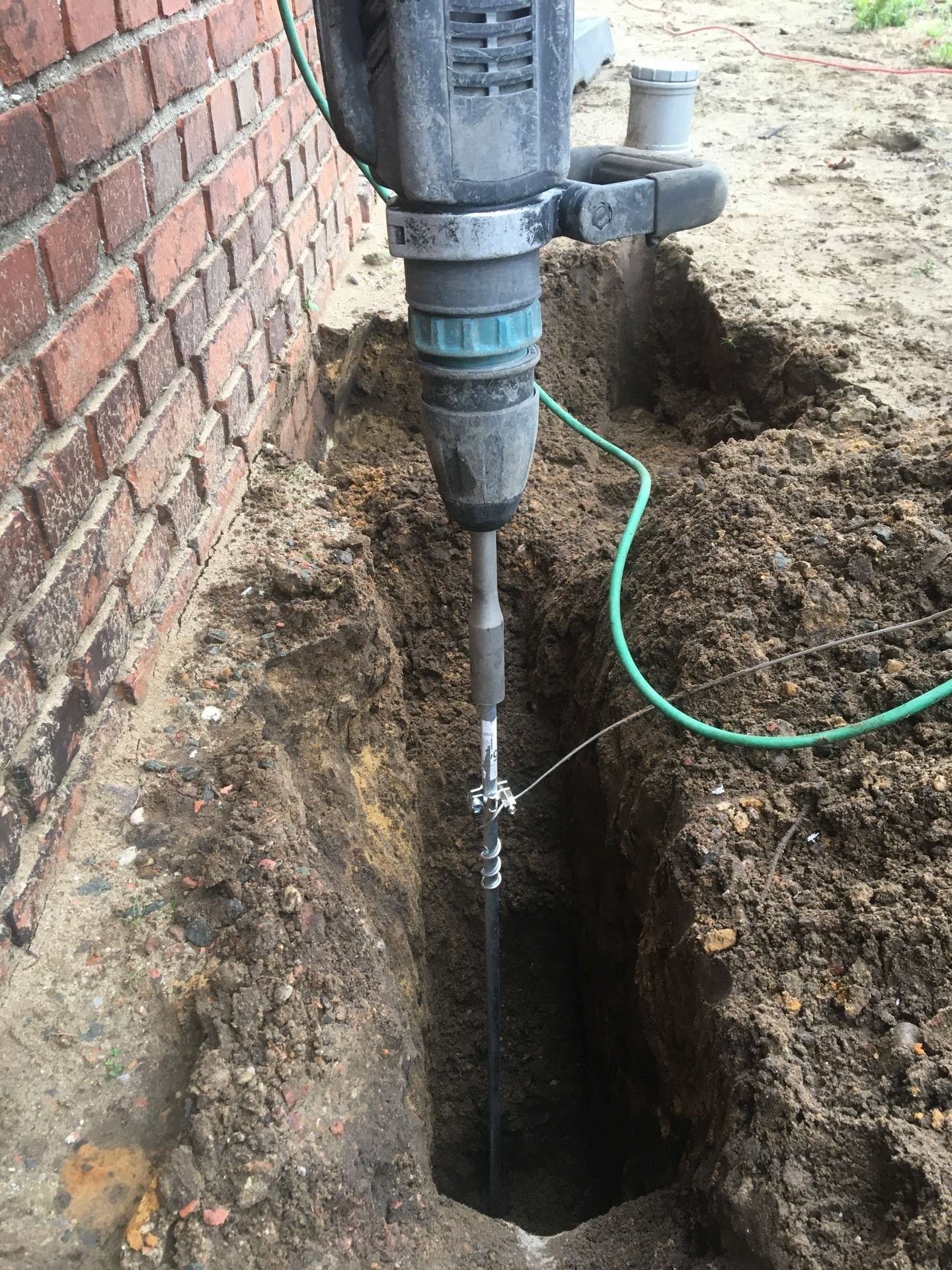 Er wordt gebruik gemaakt van een boormachine om een gat in de grond te boren.
