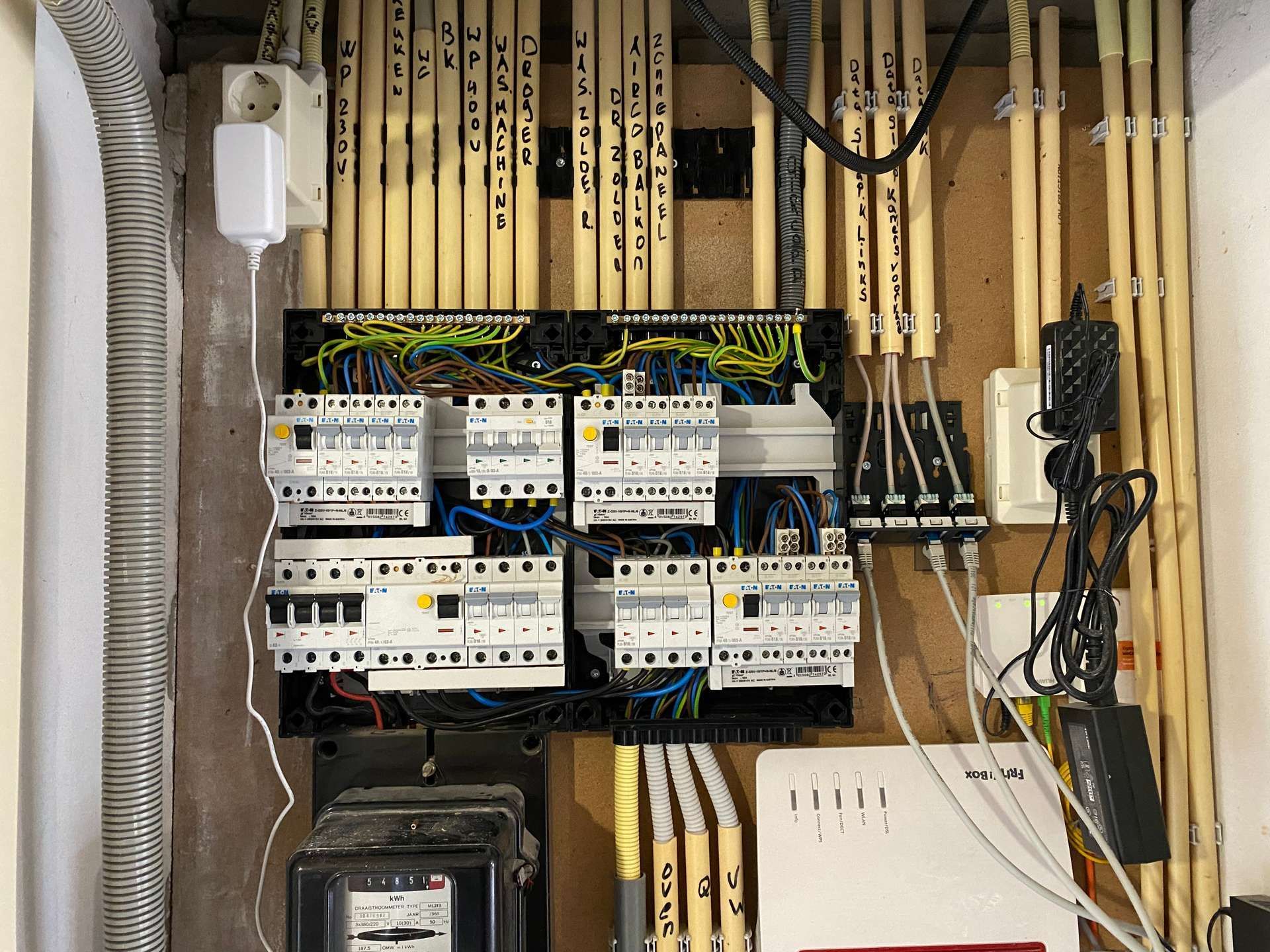 De binnenkant van een elektriciteitskast waar veel draden uit komen