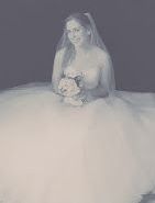 Bruid in witte strapless jurk, met bloemen, sluier en bril in haar handen, zittend.