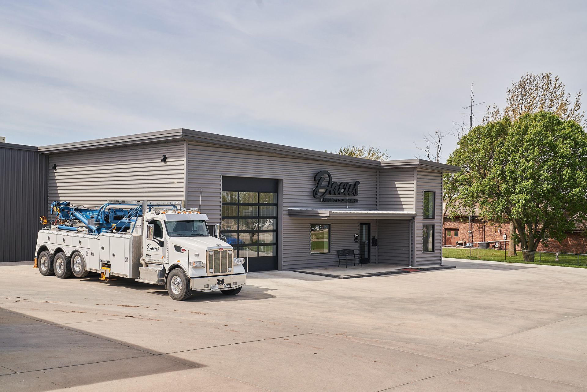 White utility truck parked outside a modern gray industrial building on a sunny day