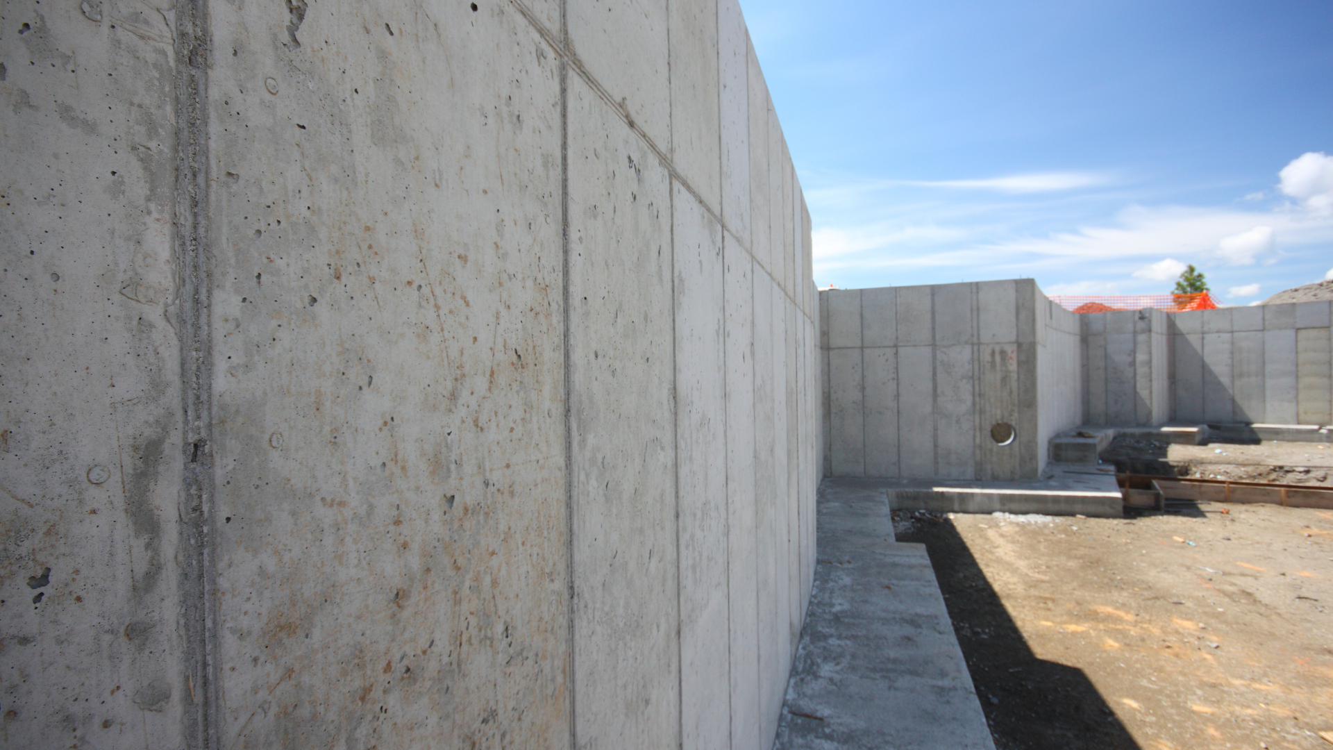 Concrete foundation walls under a bright blue sky. Construction site with unfinished floor and walls.