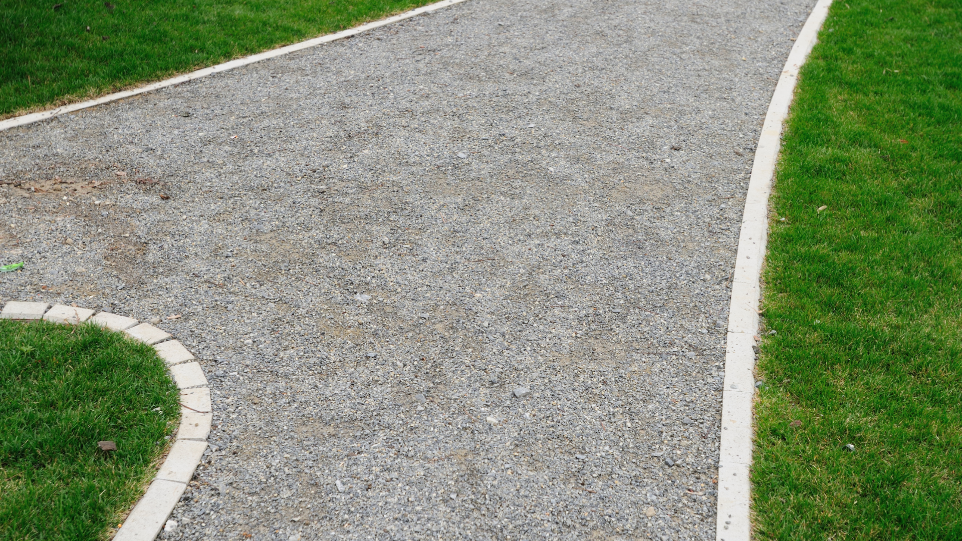 Gravel pathway bordered by light-colored edging and bright green grass.
