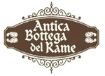 Un logo marrone di forma ovale con bordi decorativi a volute, contenente la scritta bianca 