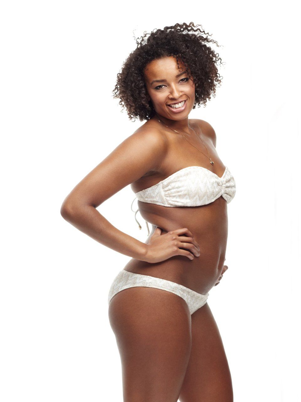 a woman in a white bikini is standing with her hands on her hips .