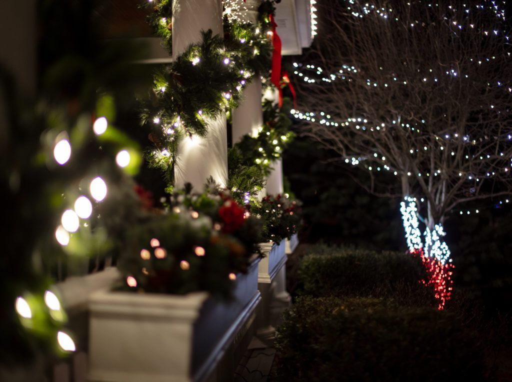 A porch decorated with christmas lights and decorations at night.