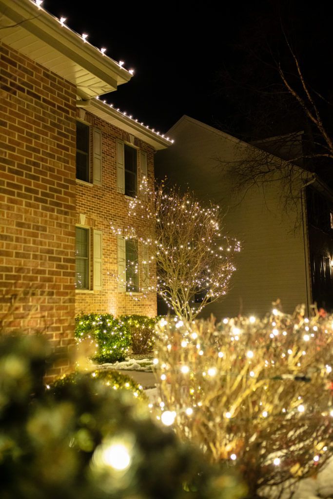 A brick house is decorated with christmas lights at night.