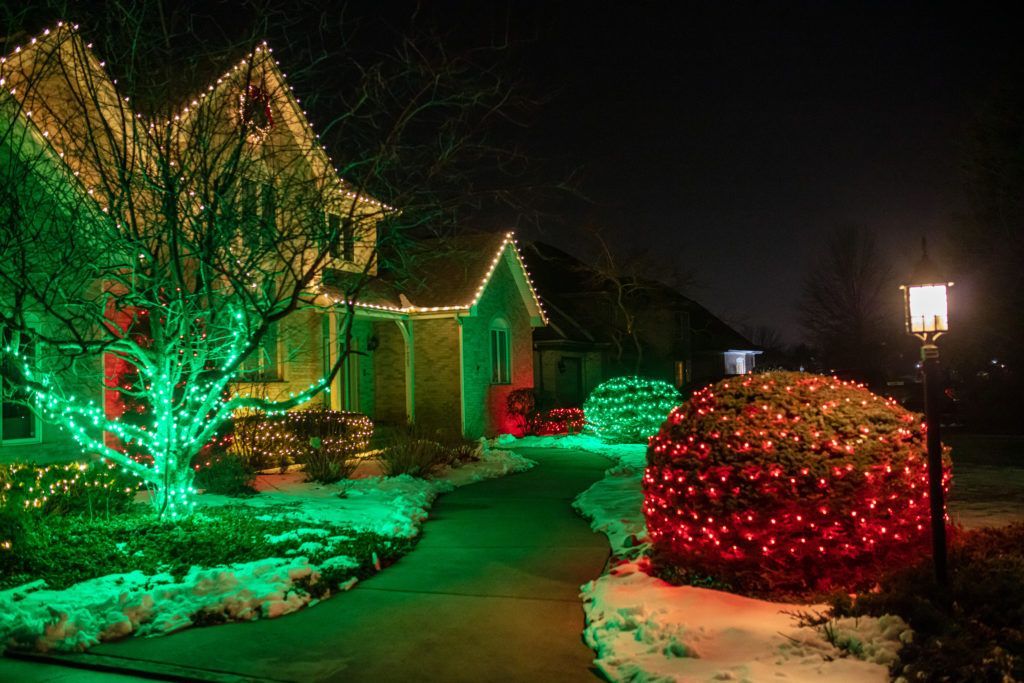 A house is decorated with green and red christmas lights at night.