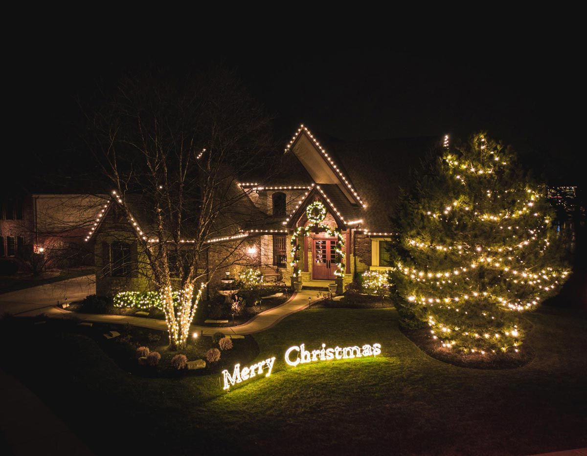 A house is decorated with christmas lights and a sign that says merry christmas.