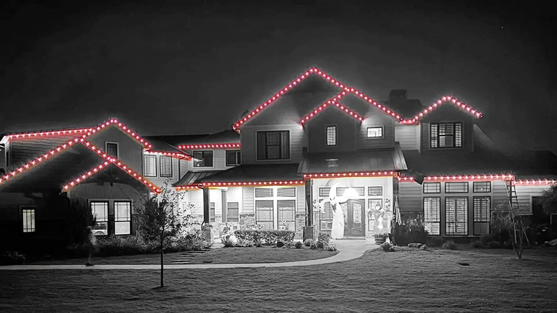 A house with christmas lights on the side of it at night.