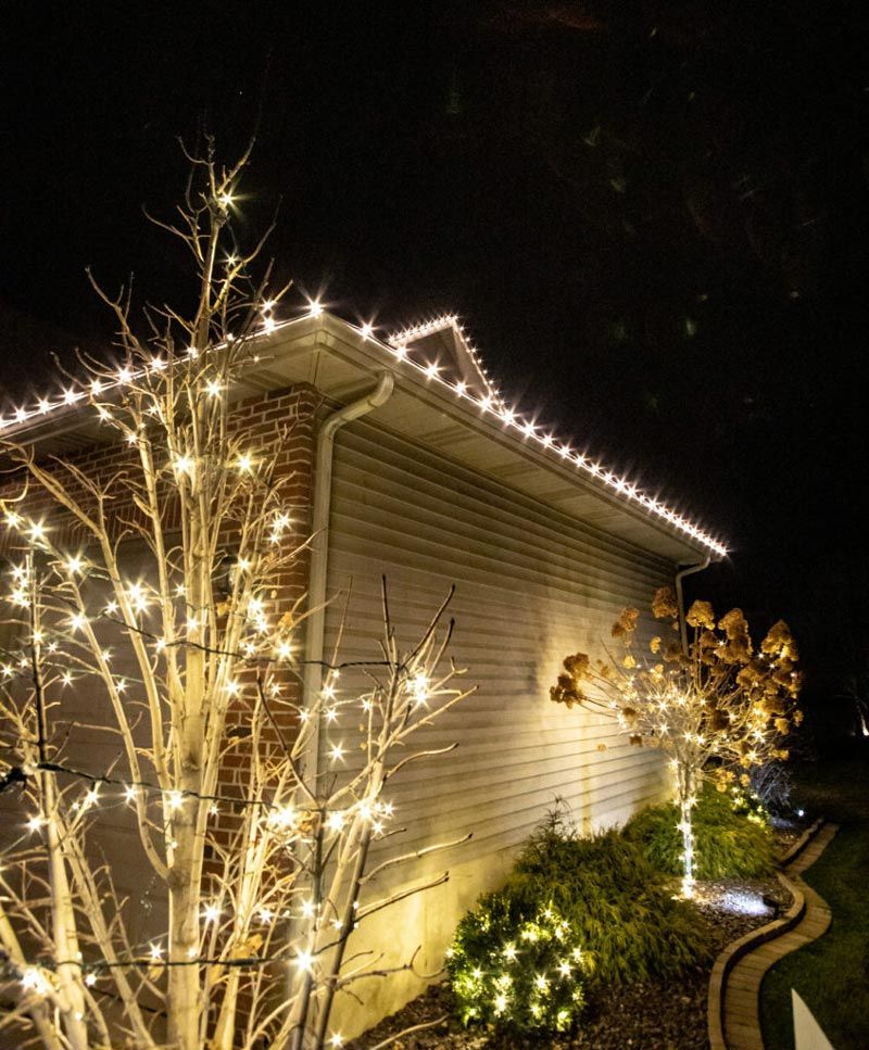 A house with christmas lights on the side of it at night.