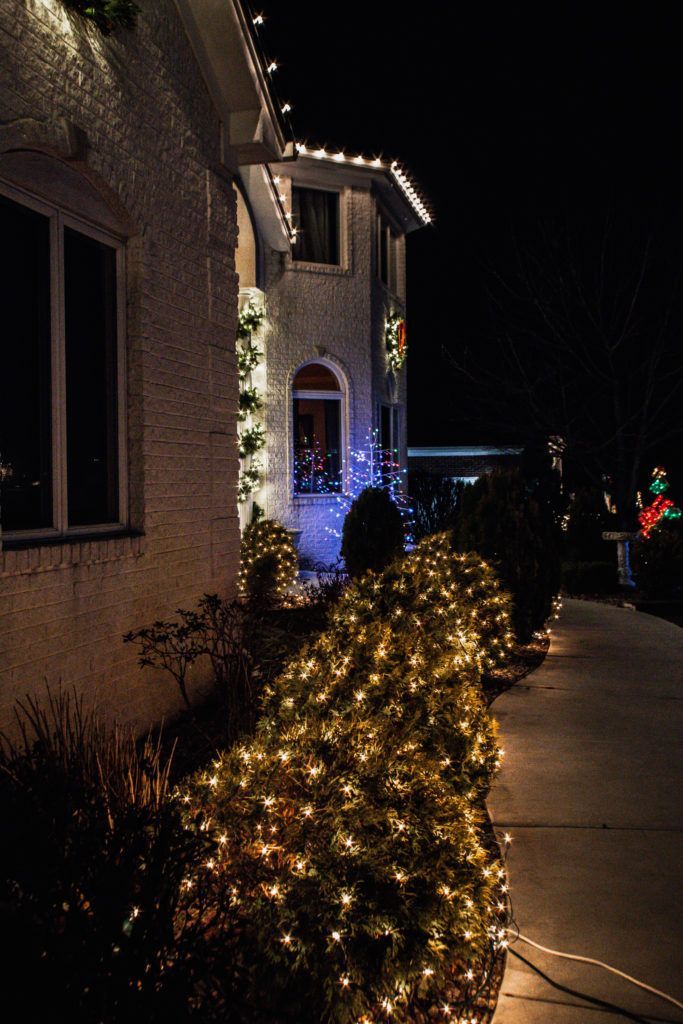 A house with christmas lights on the side of it at night.