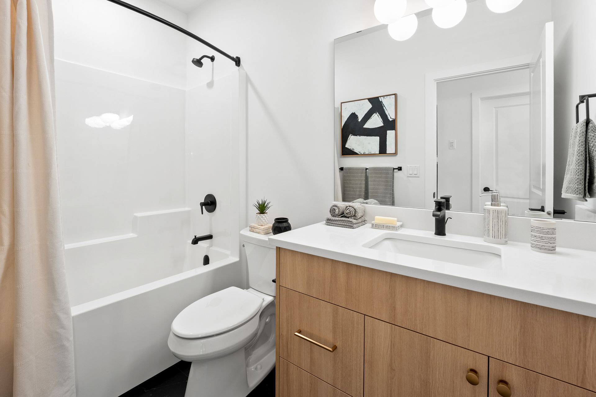 Modern white bathroom with tub, vanity, and wood cabinet under bright mirror lights