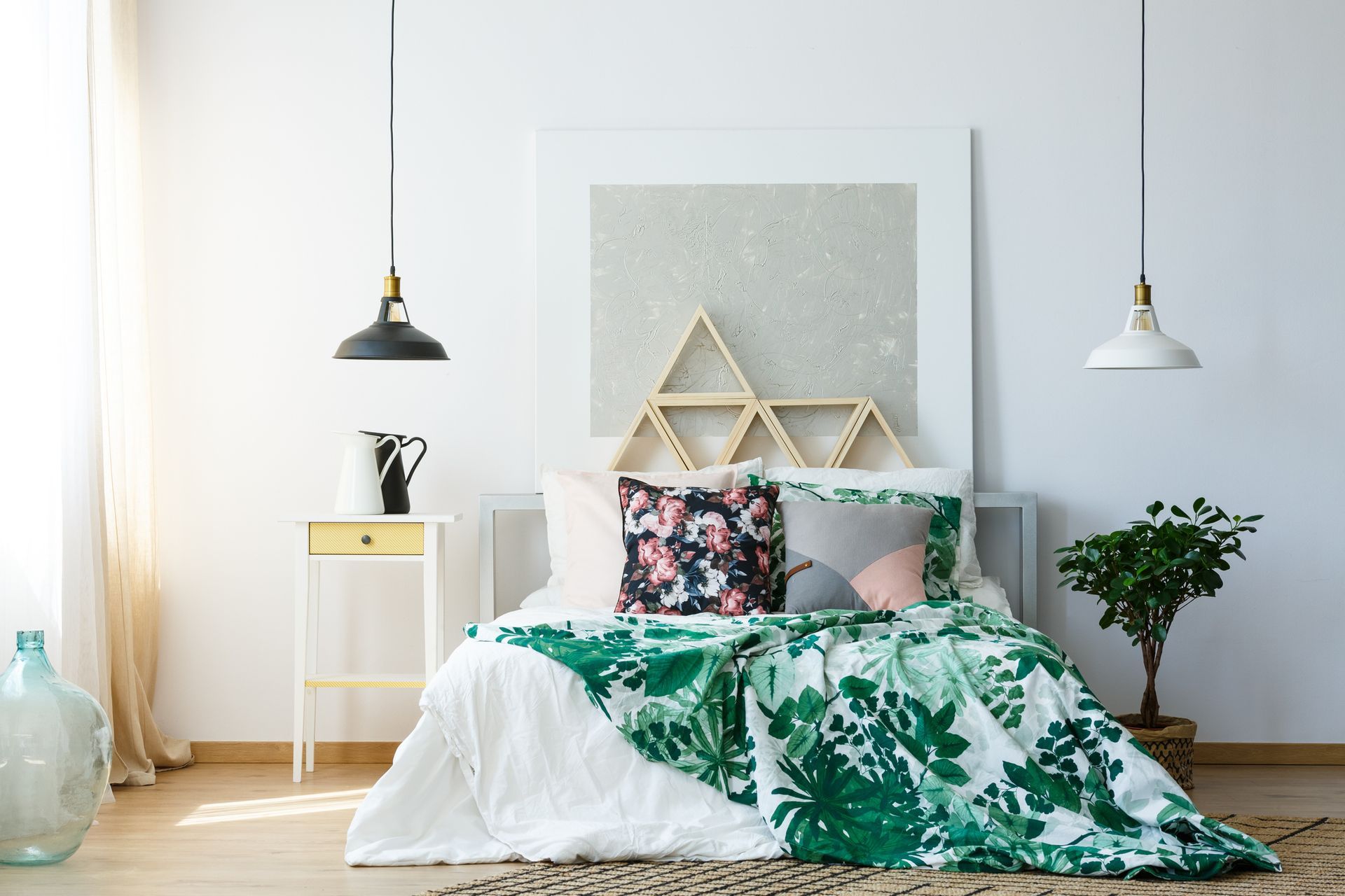 Minimalist bedroom with white bed, green floral bedding, pendant lights, and potted plant