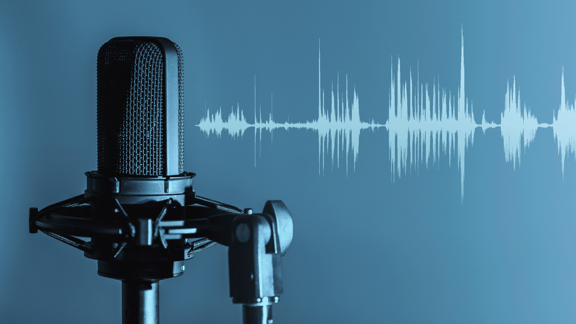 A microphone is sitting on a stand in front of a blue wall.