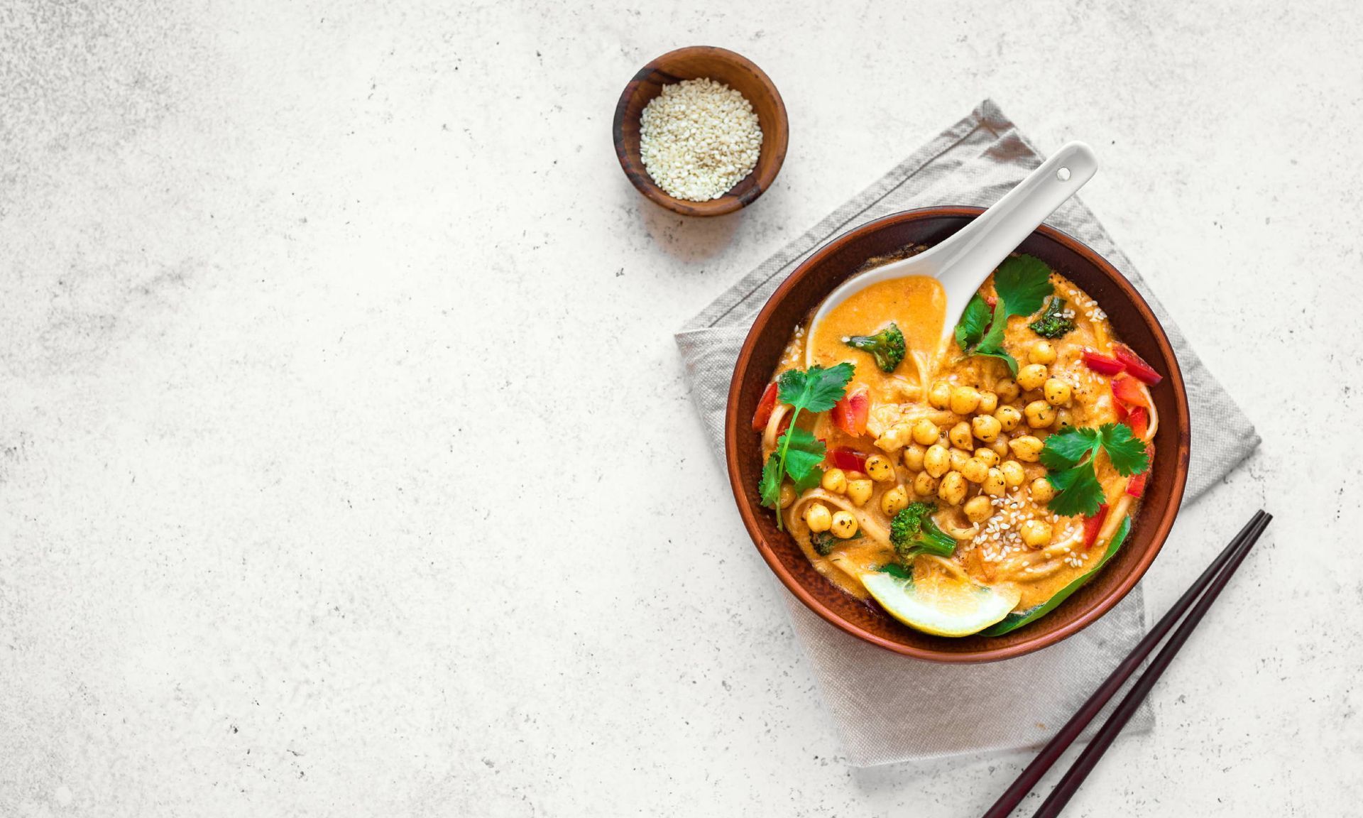 A bowl of soup with chopsticks and a spoon in it.