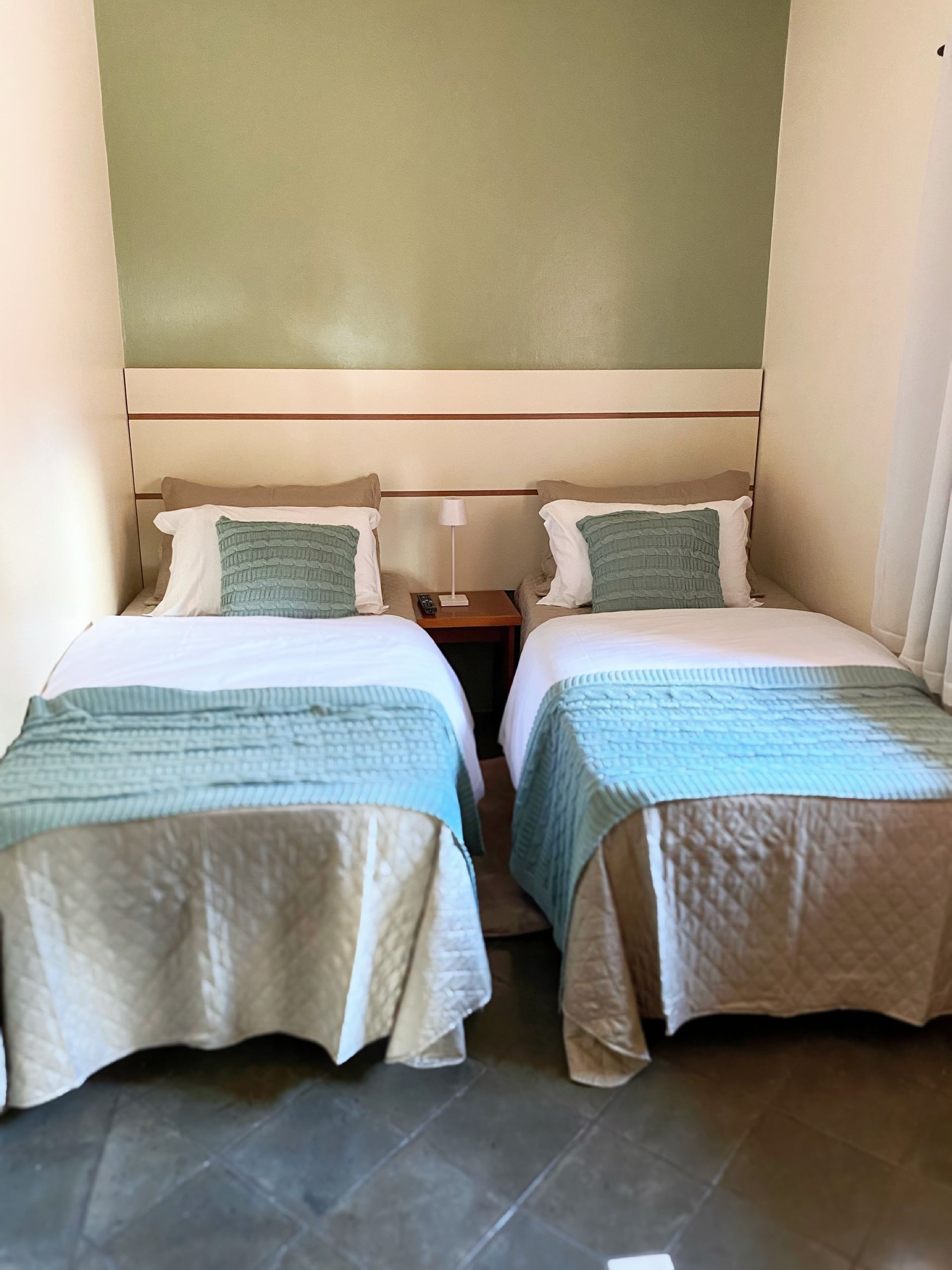 Um quarto com duas camas e uma mesa de cabeceira.