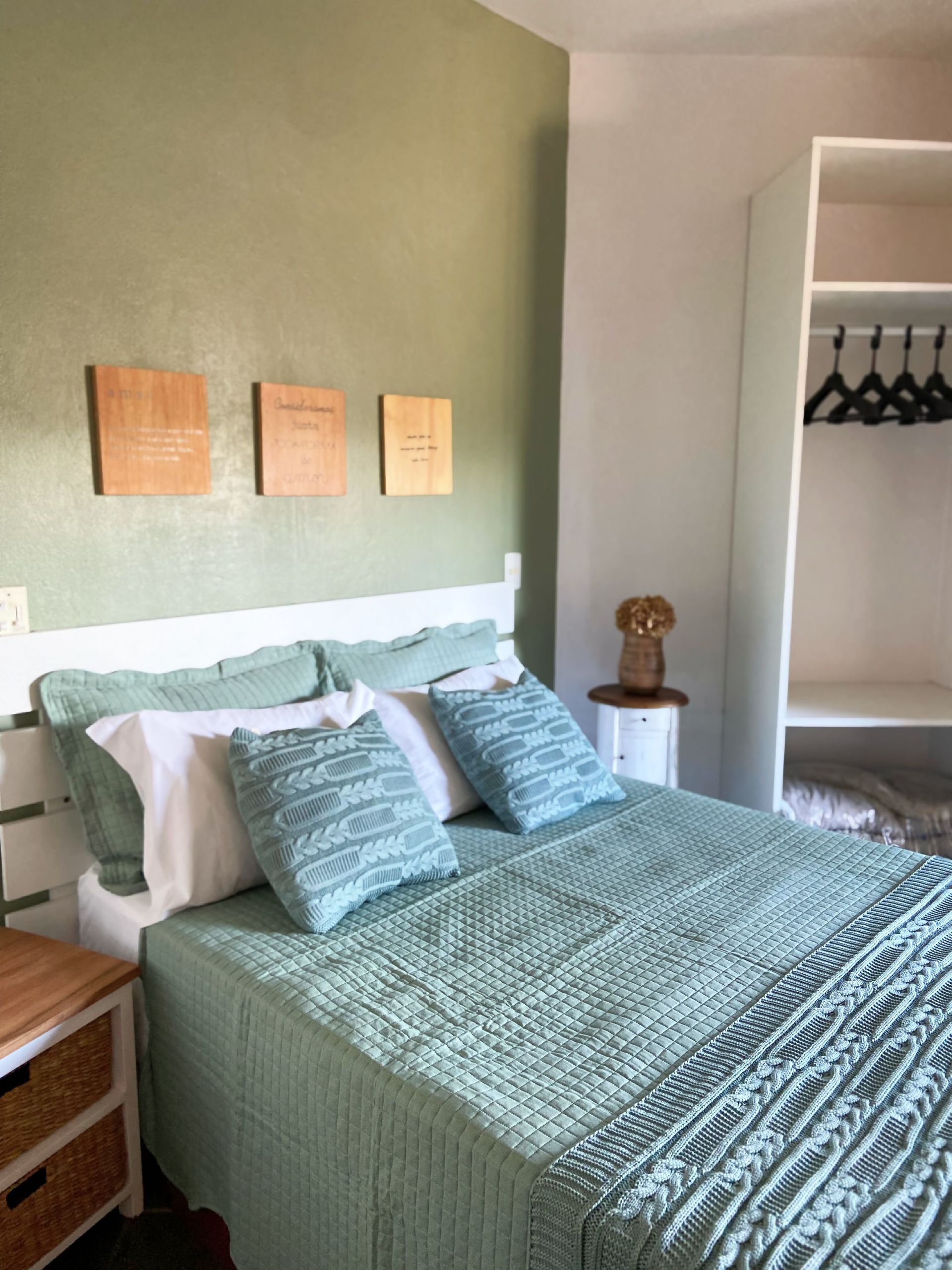 Um quarto com uma cama com um cobertor verde e travesseiros