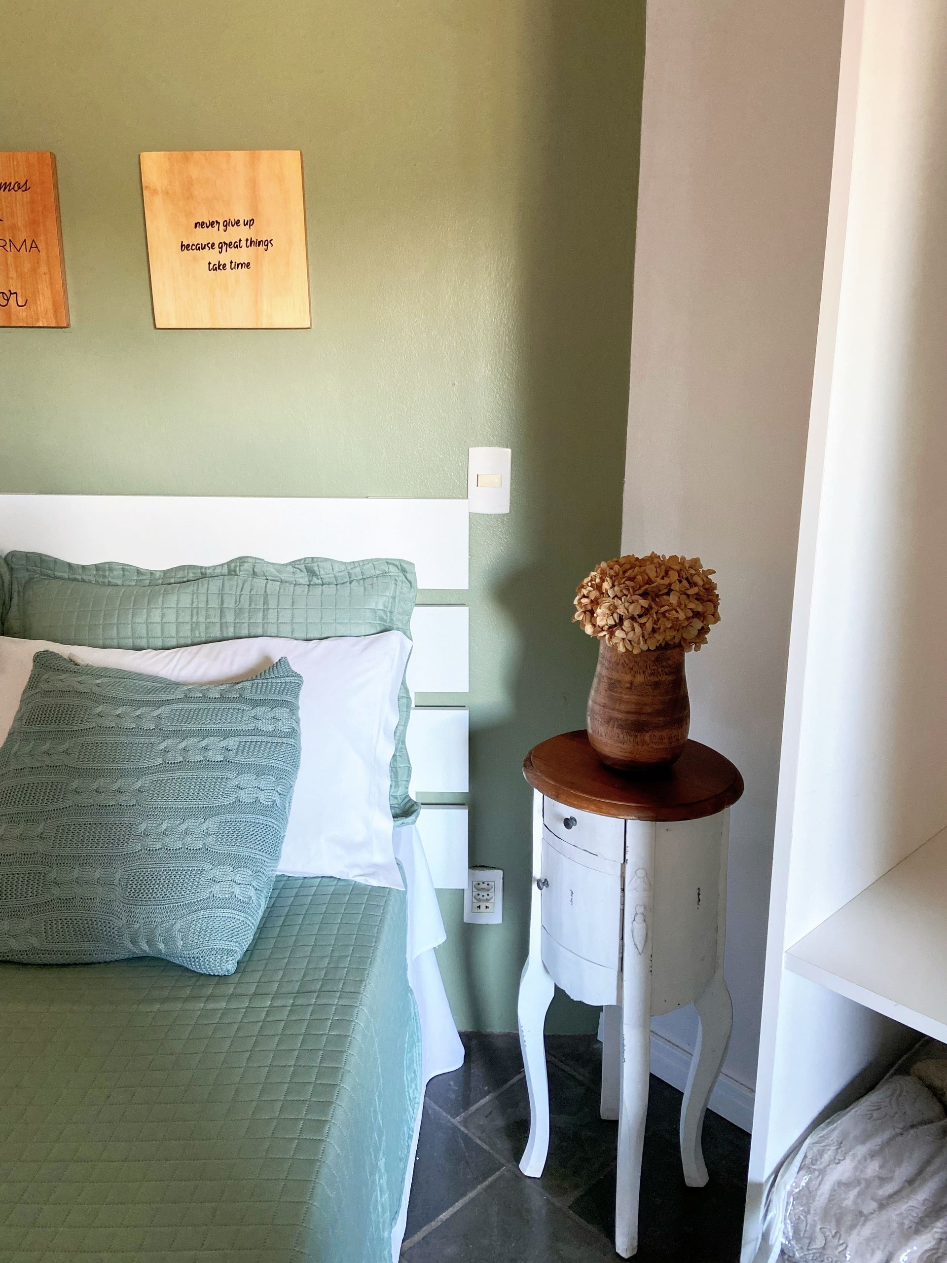 Um quarto com uma cama e uma mesa de cabeceira com um vaso de flores