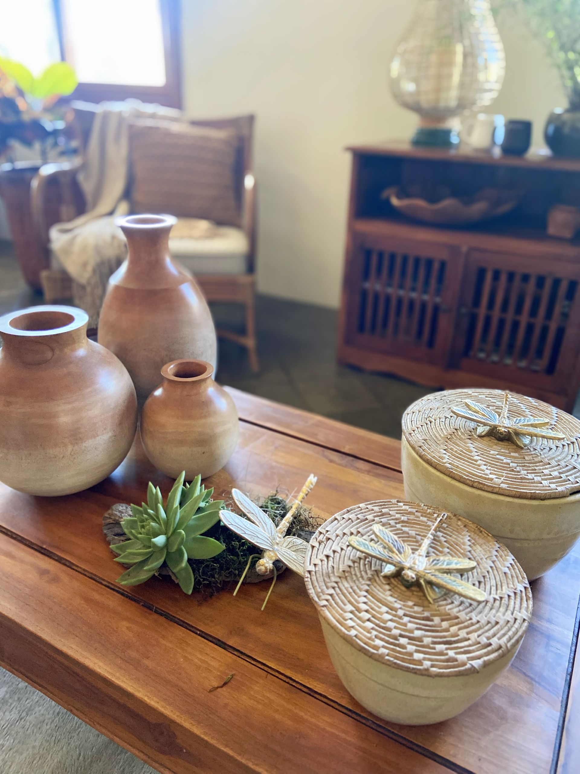 Uma mesa de madeira com vasos e cestos em uma sala de estar.