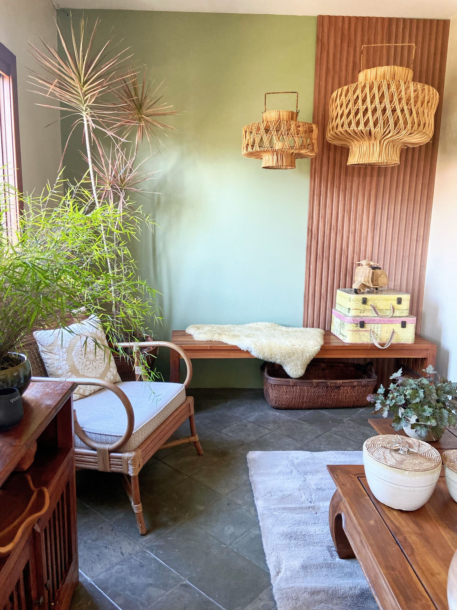 Uma sala de estar com um banco, cadeira, mesa e plantas.