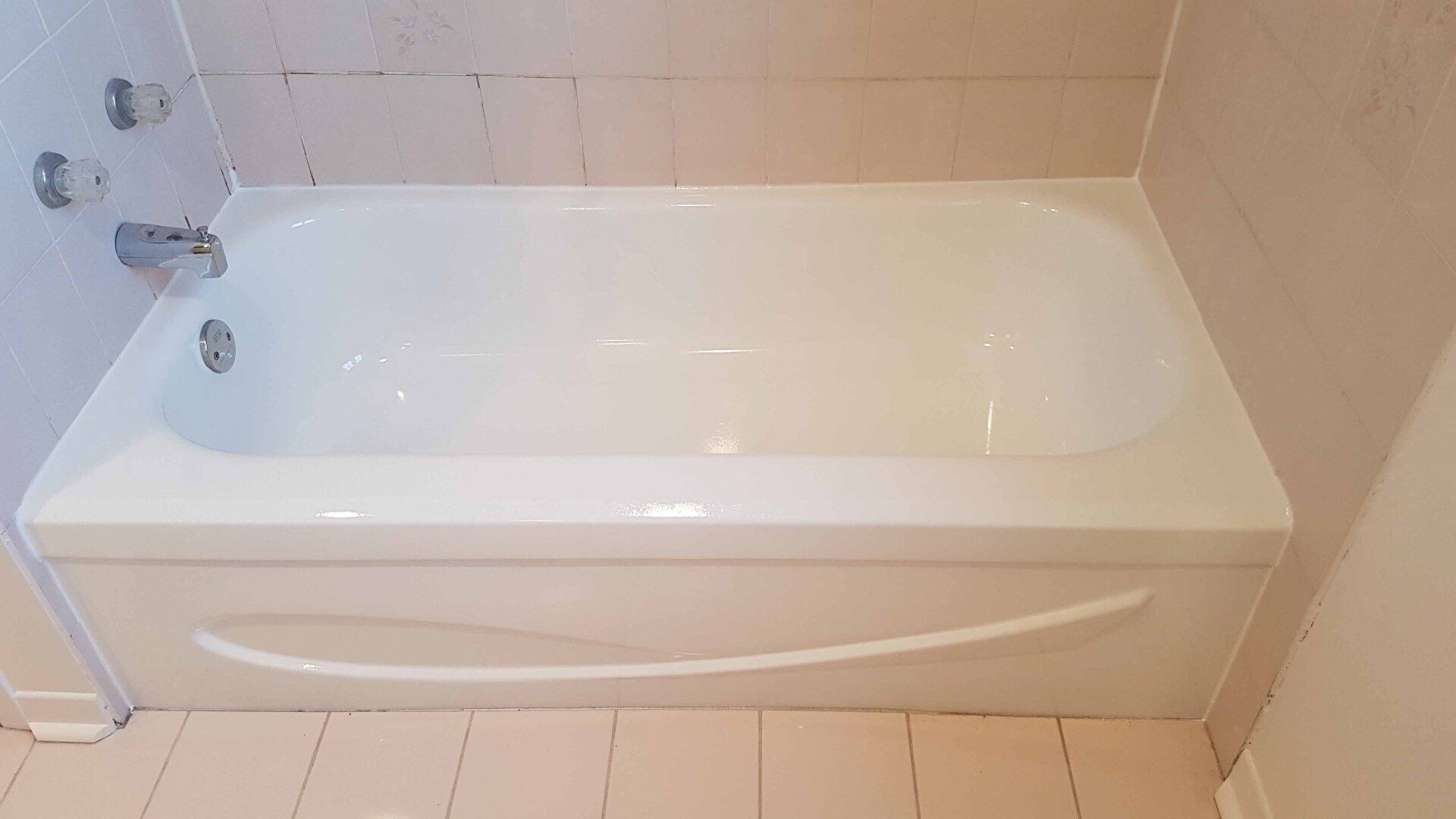 Baignoire blanche avec robinet chromé dans une salle de bain carrelée beige