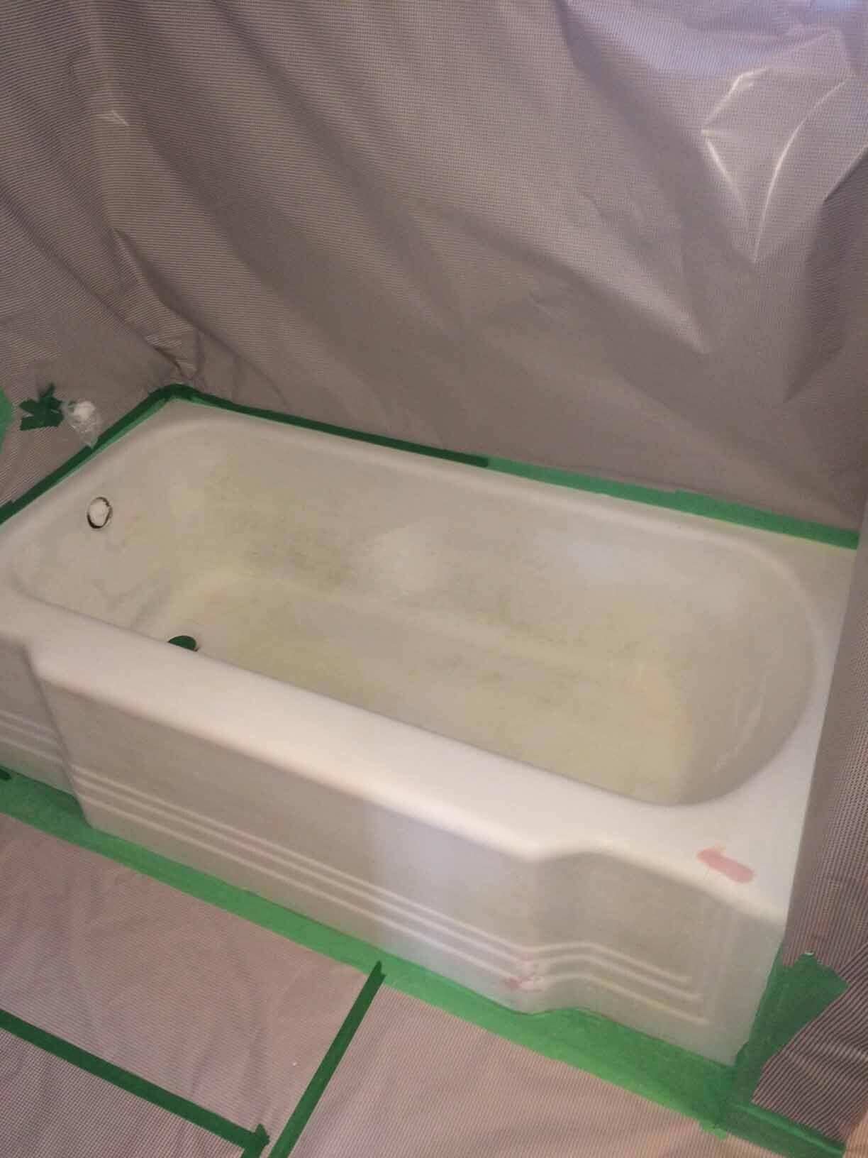 Baignoire blanche entourée de ruban adhésif de peintre vert dans une pièce en rénovation