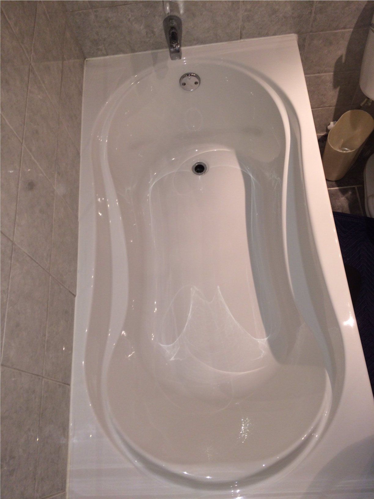 Baignoire blanche dans une salle de bains carrelée de beige, vue de dessus.