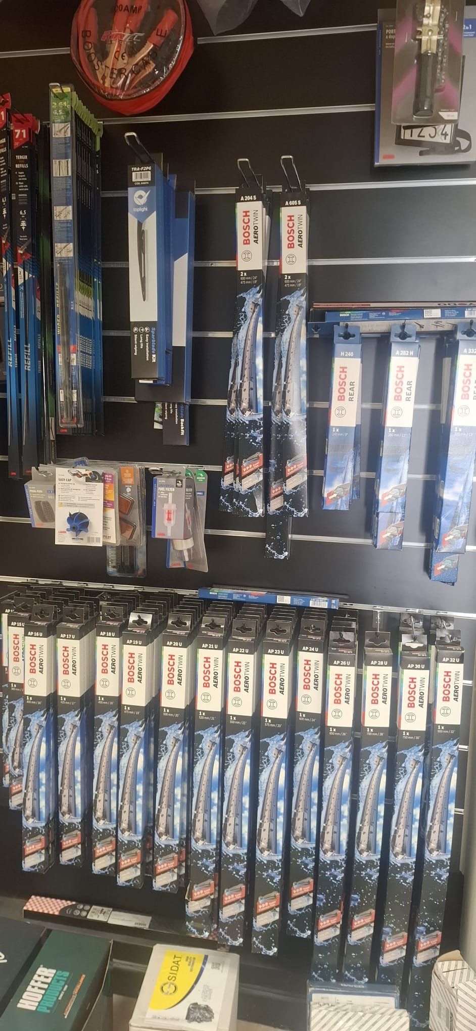 Canne da pesca blu e relativi accessori esposti su uno scaffale a muro di un negozio.