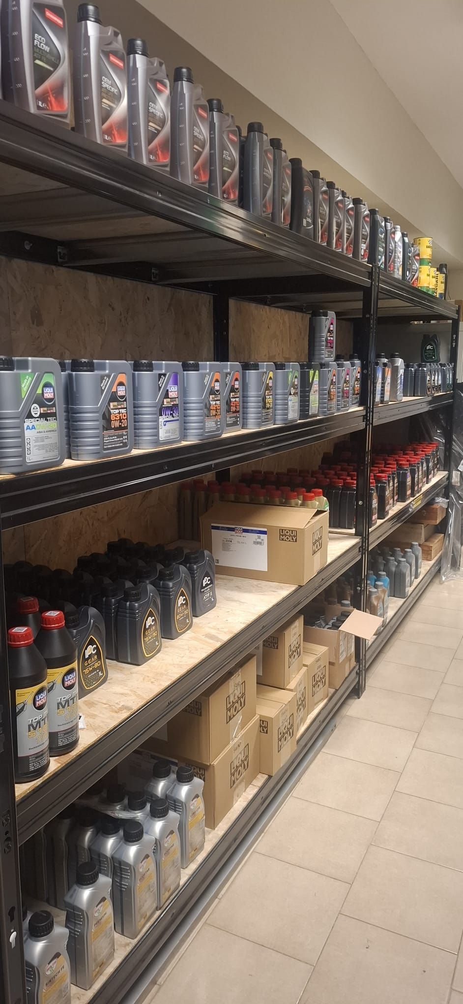 Scaffali pieni di bottiglie e scatole di fluidi per autoveicoli in una corsia di un negozio.