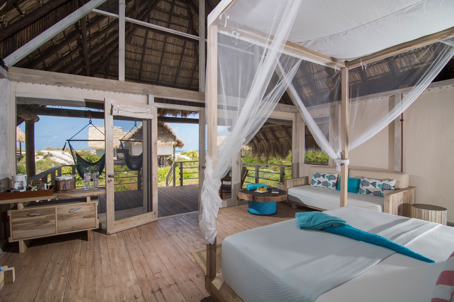 Bedroom with a canopy bed, ocean view, and rustic wooden furniture.