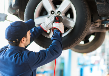 Person attaching a tire to a car | BG Automotive